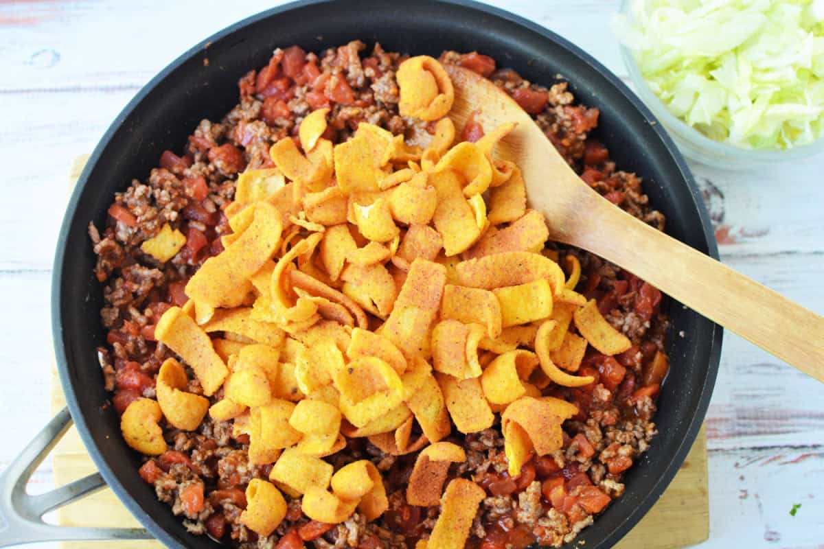 skillet filled with cooked ground beef topped with fritos