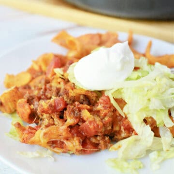 Walking Taco Casserole on a white plate topped with shredded lettuce and sour cream
