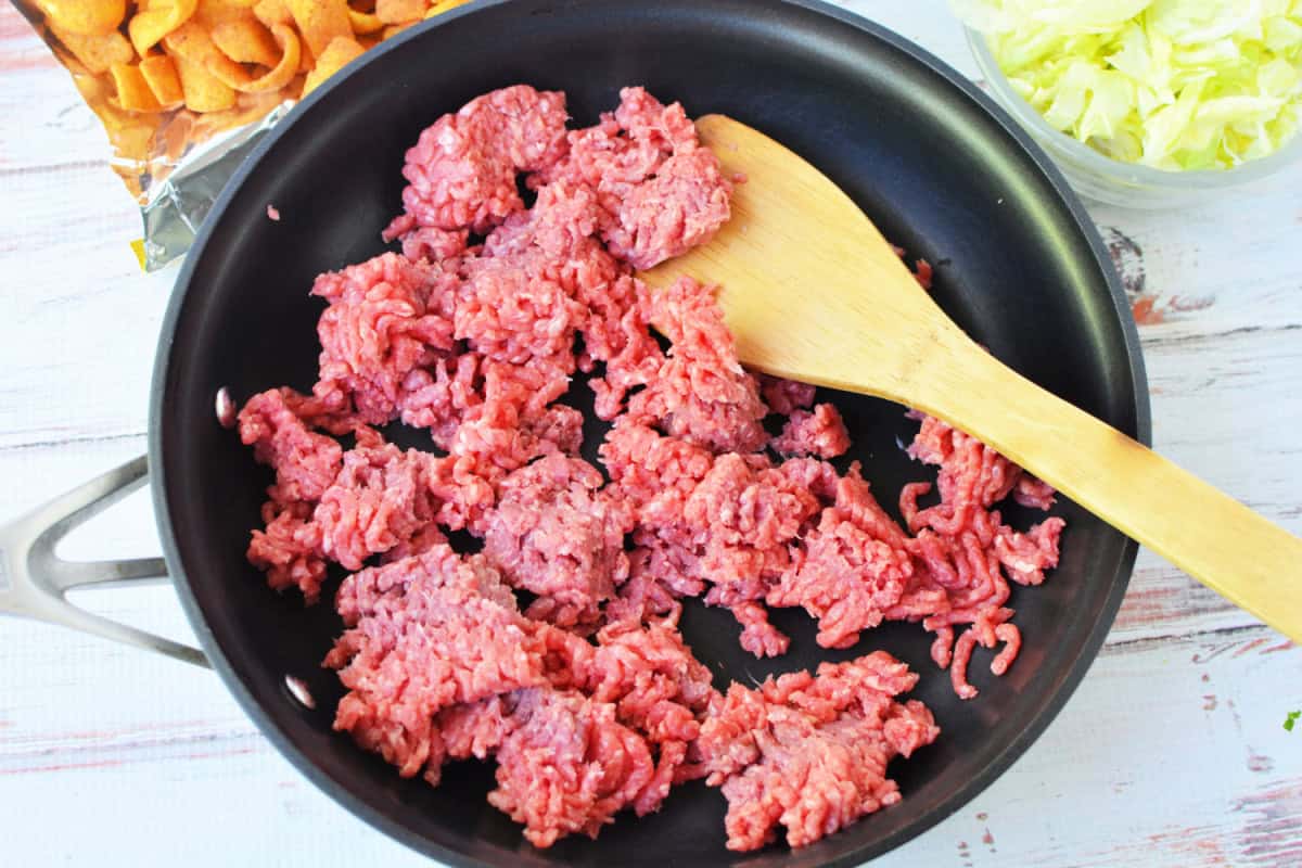 ground beef in a skillet with a wooden spoon