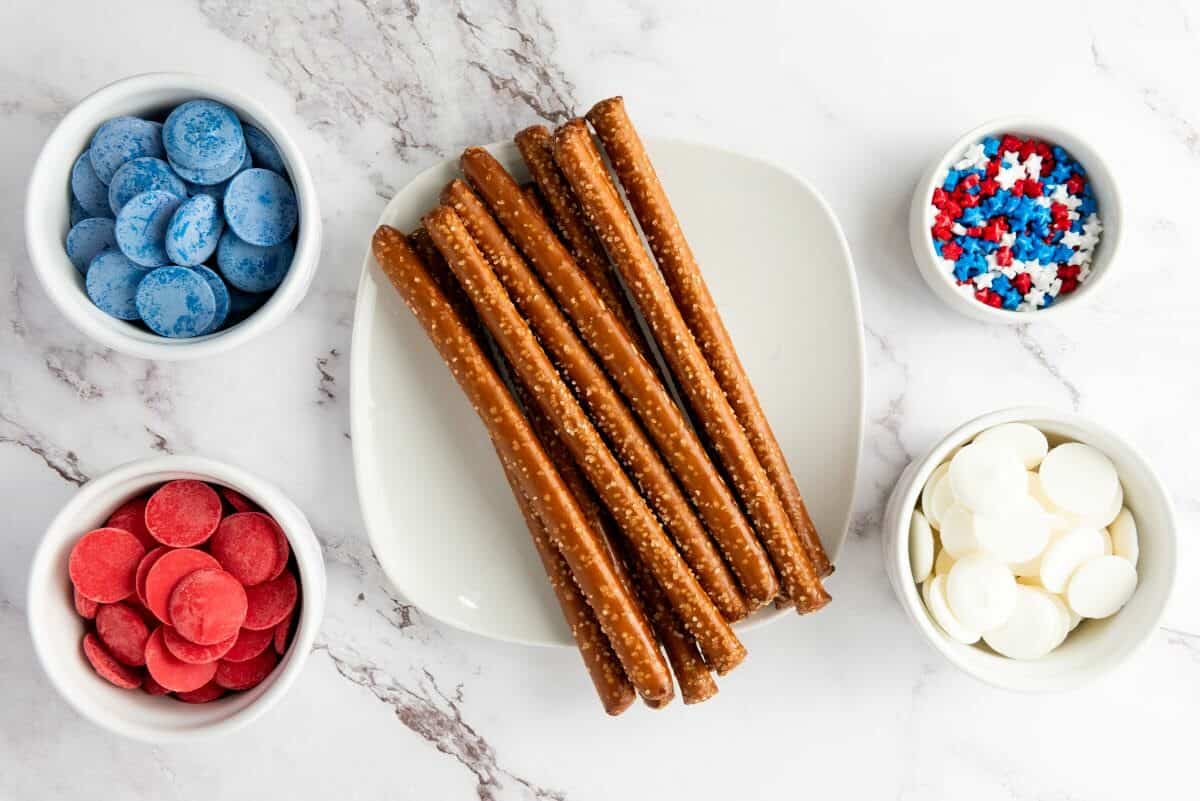 pretzel rods, bowls of white chocolate, red and blue and sprinkles