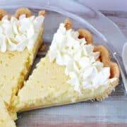 Lemon Custard Pie in a pie plate topped with whipped cream