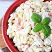 Chicken Macaroni Salad in a red bowl with fresh basil on top