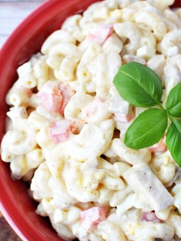 Chicken Macaroni Salad in a red bowl with fresh basil on top