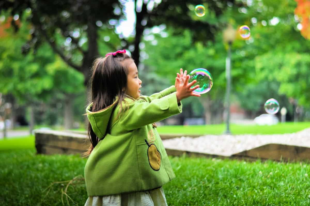 kid chasing a bubble outside