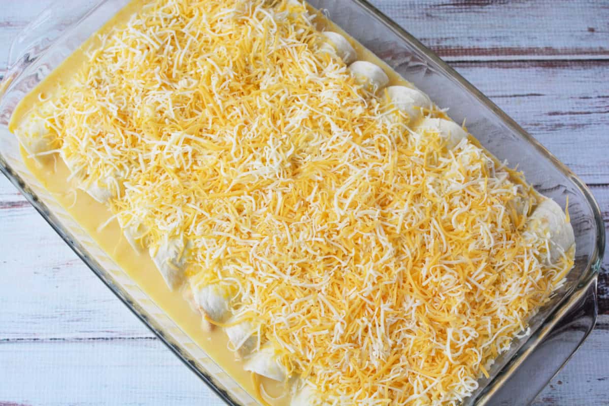 Sour Cream Enchiladas in a casserole dish topped with shredded cheese