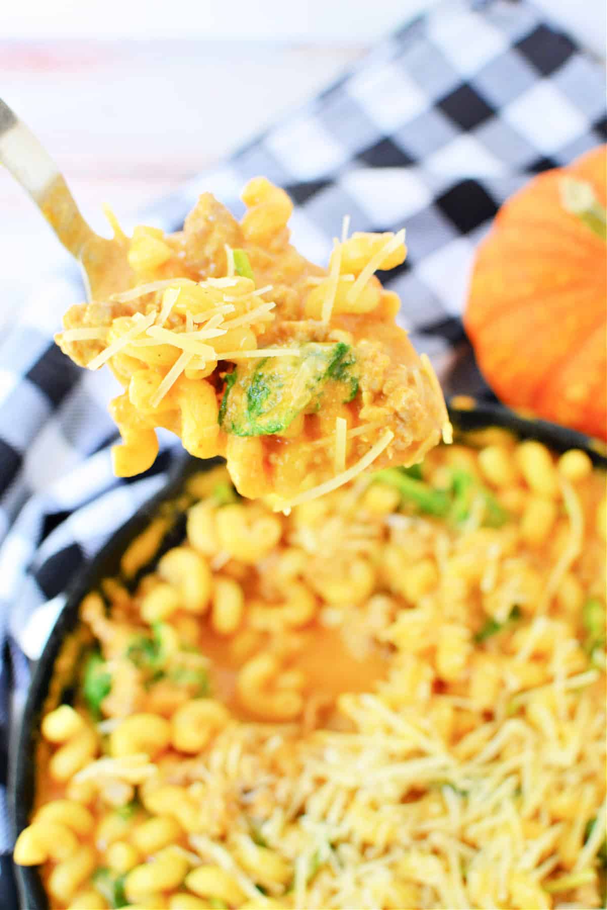 A fork full of Creamy Italian Sausage Pasta with Pumpkin and spinach topped with parmesan cheese