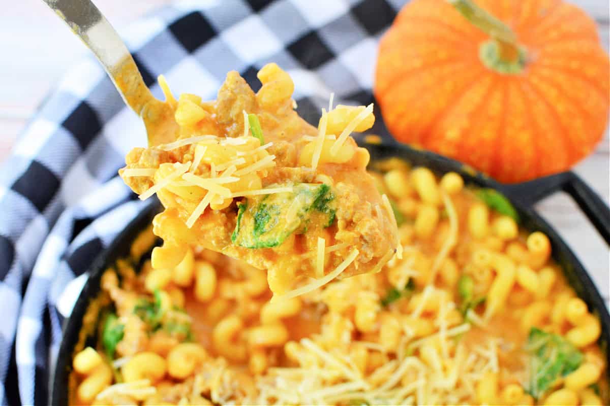 A fork full of Creamy Italian Sausage Pasta with Pumpkin and spinach topped with parmesan cheese