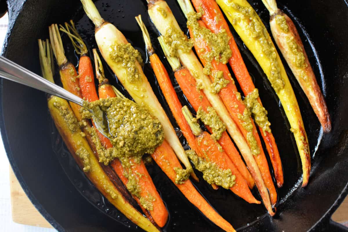 Roasted Carrots in a cast iron pan covered in pesto sauce