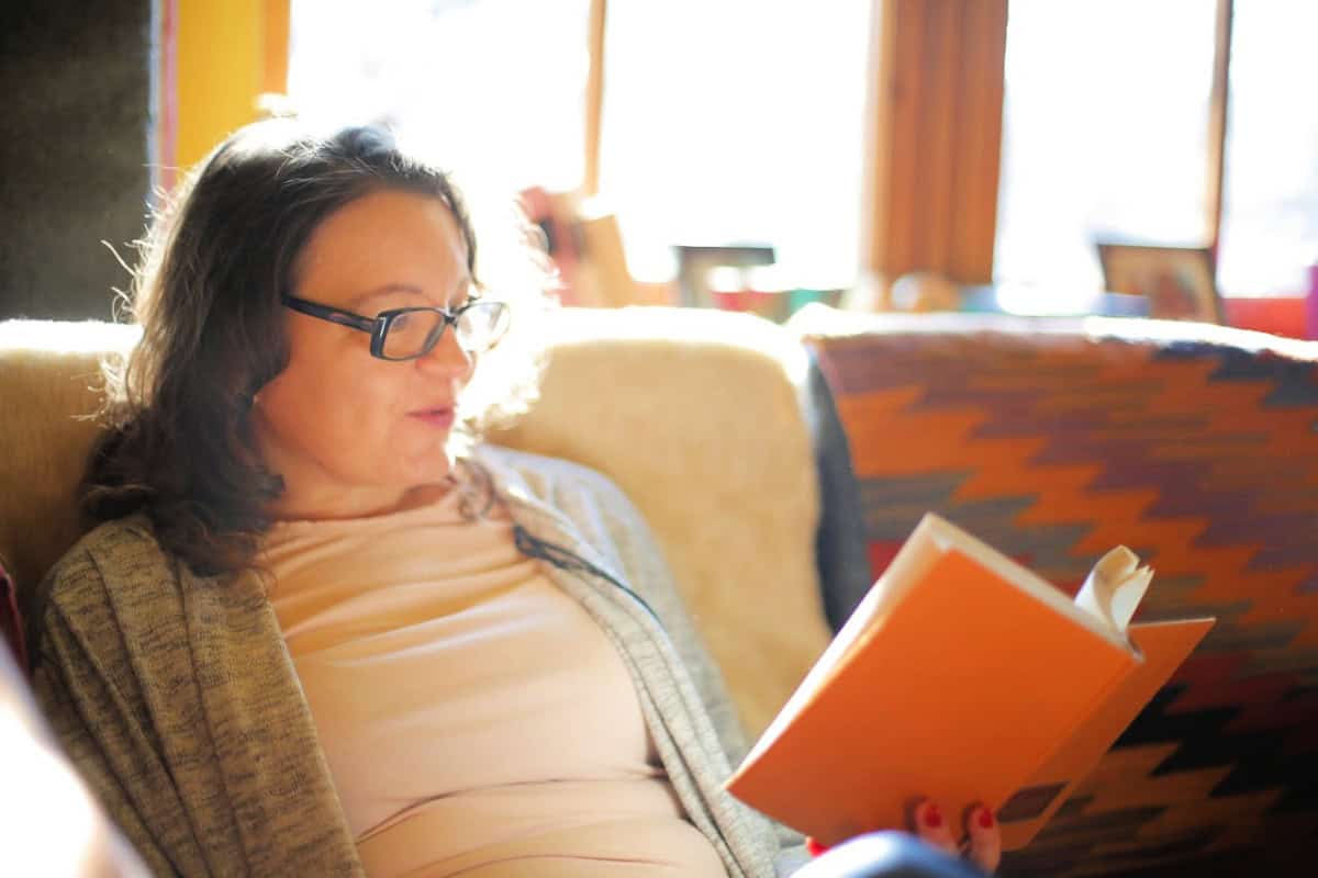woman reading a book on her sofa