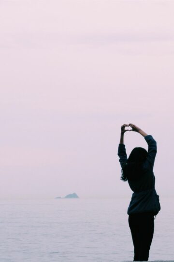 woman making a heart at sunset happy and joy