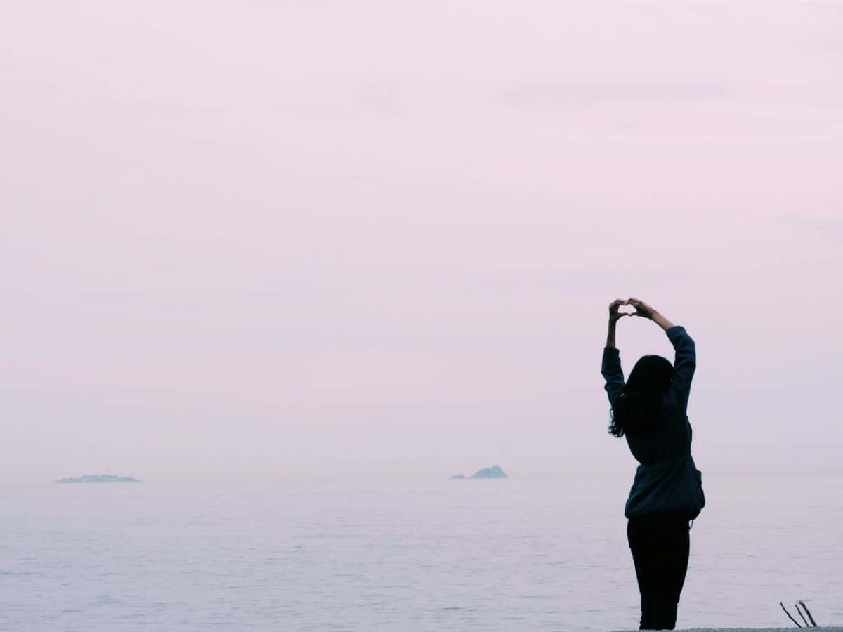 woman making a heart at sunset happy and joy 
