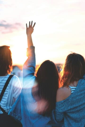 girls together at sunset being happy