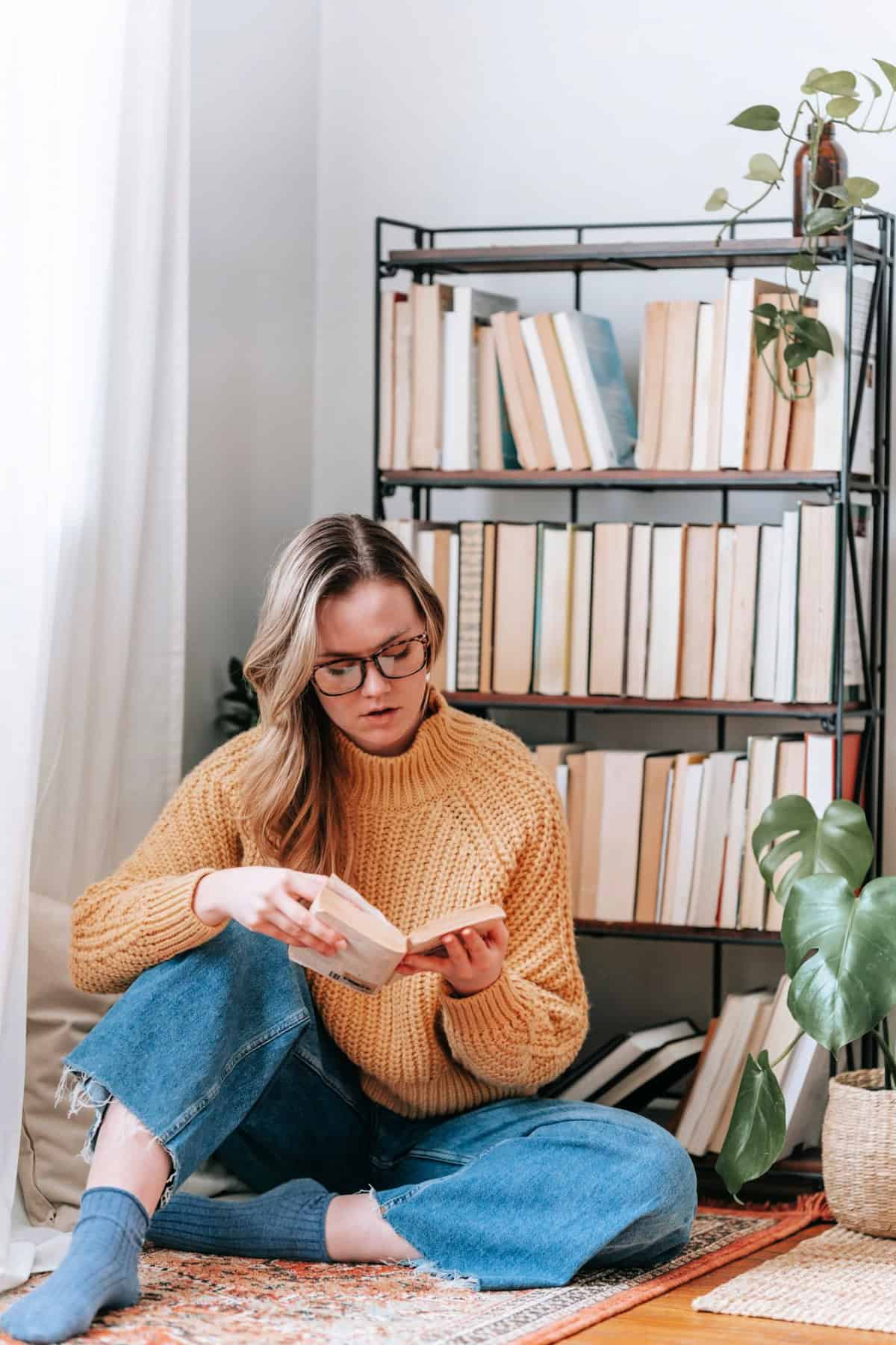 woman reading a book near a bookshelf