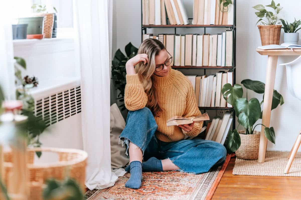woman reading a book near a bookshelf