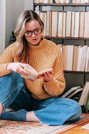 woman reading a book near a bookshelf