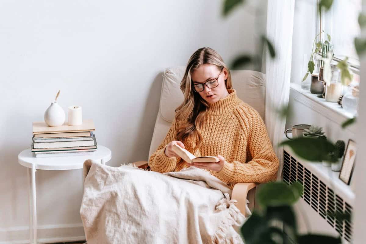 woman reading a book near a bookshelf