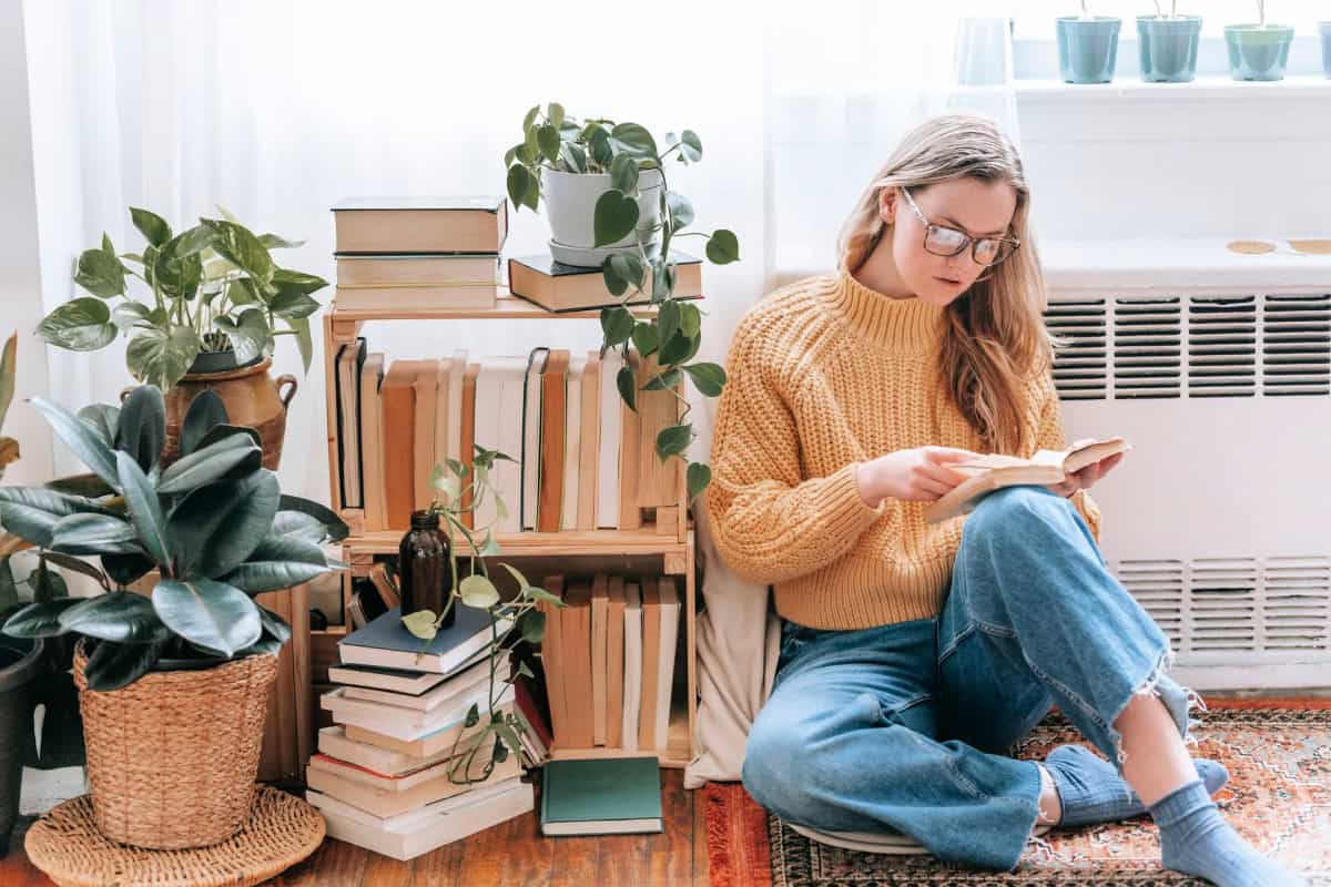 woman reading a book near a bookshelf