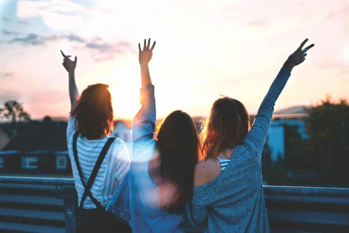 girls together at sunset being happy