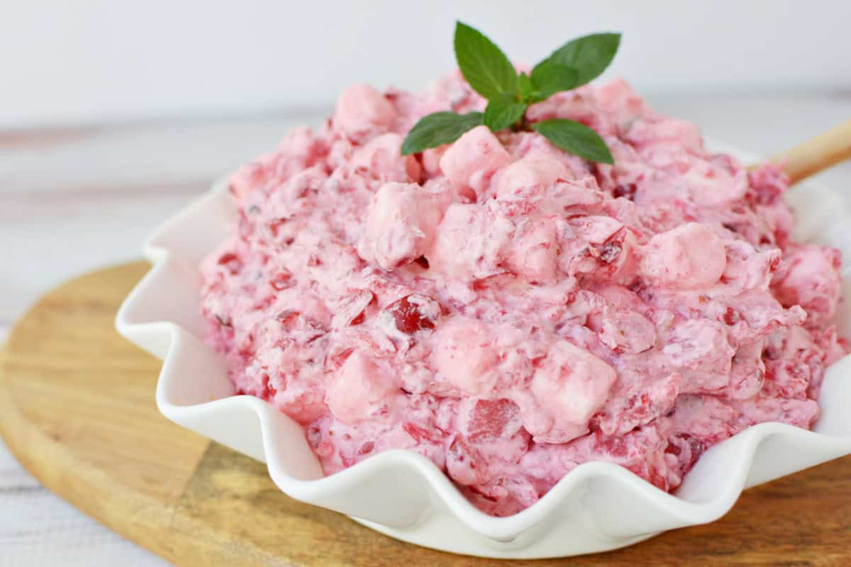 Cranberry Fluff in a white serving bowl with a wooden spoon