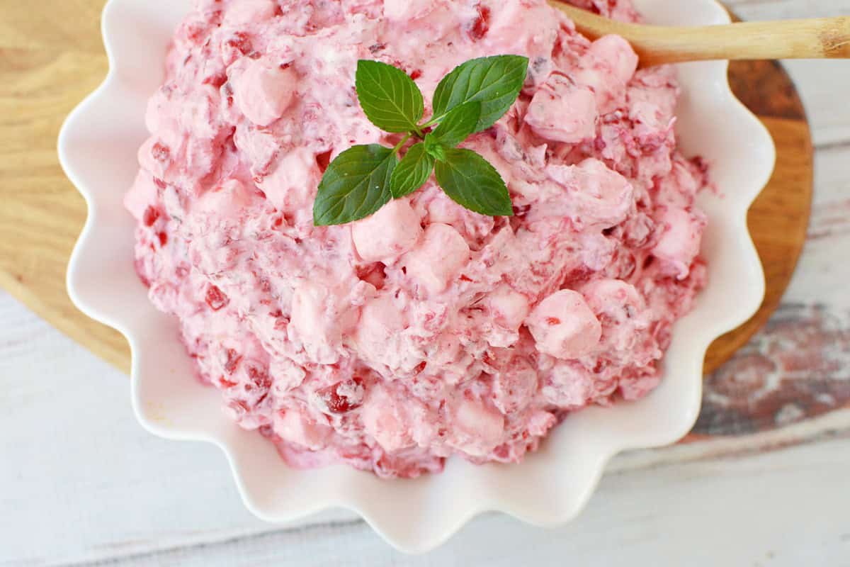 Cranberry Fluff in a white serving bowl with a wooden spoon